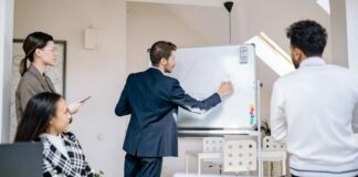 A marketing team leader standing at a whiteboard with sticky notes discussing bottom-of-the-funnel marketing.